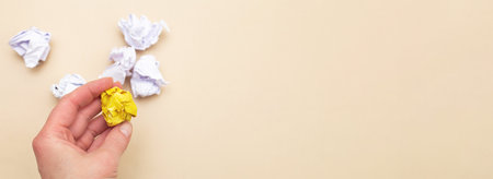female hand holding crumpled yellow and white paper as a concept creative idea and innovation on a beige backgroundの写真素材