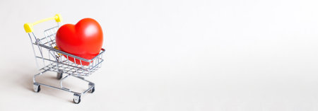Red heart in the shopping cart or trolley isolated on beige background. Shopping for wedding, womens day concept, gifts for Valentines Day. Bannerの写真素材