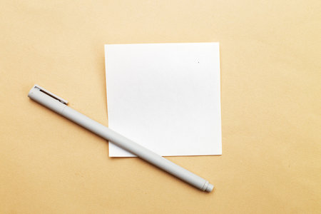 Top view of blank note paper with pen on beige background. Copy space for your text. Writing ideas, to do list or plans conceptの写真素材