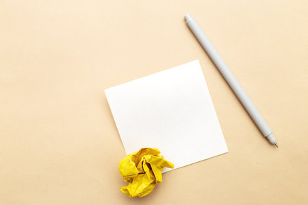 crumpled yelllow paper with a pen and note for writing on beige background as a concept creative idea and innovation. Writing ideas, to do list or plans concept. Copy space for your text.の写真素材