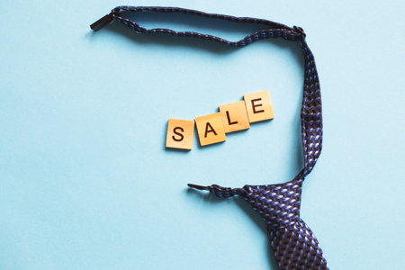 the word sale made by wooden cubes on a blue background with a tieの写真素材
