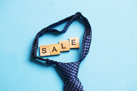 the word sale made by wooden cubes on a blue background with a tieの写真素材