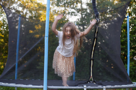 a Little child girl jumping on the trampoline in the back yardの写真素材