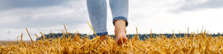 barefoot girl with sneakers and cardboard cup with coffee in hand standing in the agricultural field...