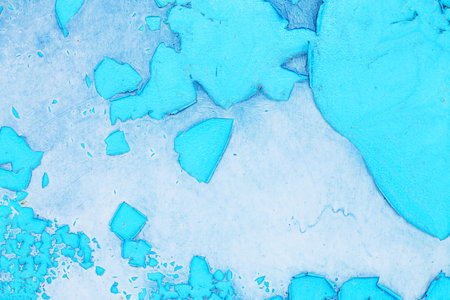 Old blue turquoise paint peeling from concrete or metal wall background. Texture of an old grunge plate with cracked paint with a hole.の写真素材