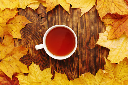 autumn leaves with a cup of tea or coffee on a wooden background with copy space.の写真素材