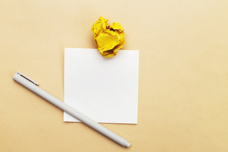 crumpled yelllow paper with a pen and note for writing on beige background as a concept creative...