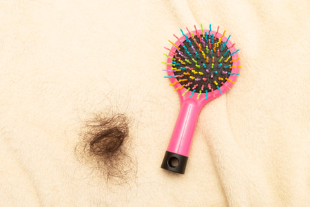 Hair loss a plastic multicolored comb on a beige background with copy space close up.の写真素材
