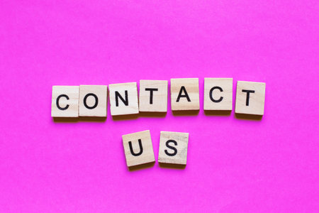 Word contact us made from wooden cubes on a pink paper backgroundの写真素材