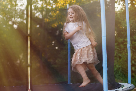 a Little child girl jumping on the trampoline in the back yardの写真素材