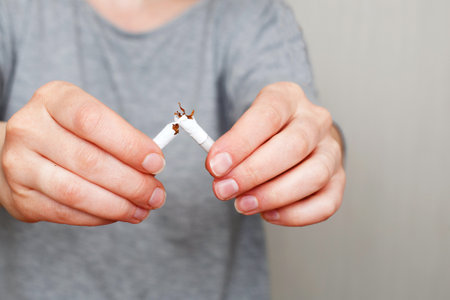 young woman holding a broken cigarette in her hands closeの写真素材