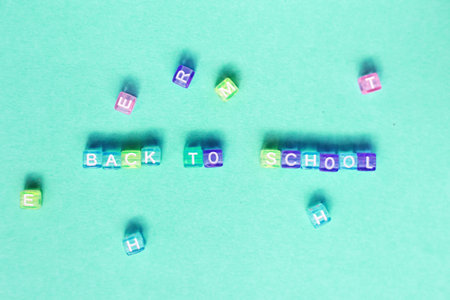 The inscription back to school made by multicolor plastic cubes on a blue green backgroundの写真素材