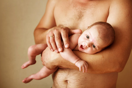 Closeup portrait of young father holding his cute newborn baby with copy space on beige background. Fathers day holiday, love, care concept.の写真素材