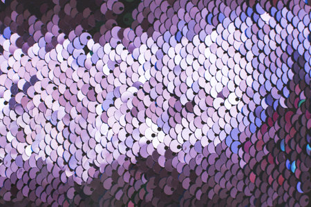 Purple abstract sequins sparkling background. Texture of sequins. Holiday wallpaper with pattern of round lilac sequins. Violet fashion glittery scalesの写真素材