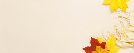 autumn leaves with a scarf on a beige background with copy space. banner.