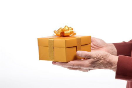 Hands of mature senior man person giving and holding gift box with golden ribbon isolated on a white background with copy space. Christmas, birthday greeting card or holiday sale conceptの素材