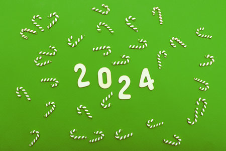 Top view of wooden numbers 2024 on green background with festive decorations of candy cane. Christmas greeting card, New Year, winter holidays sale and festive mood concept.の写真素材