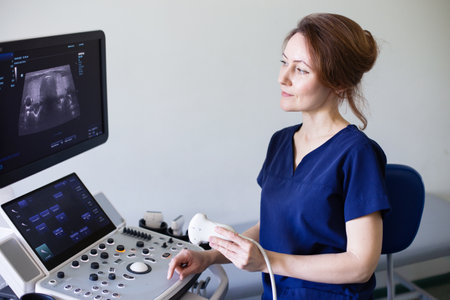 Doctor woman in uniform sitting in office in hospital with ultrasound diagnostic machine equipment and ready to examine patients doing ultrasound of thyroid gland. Ultrasound scanning diagnosticの写真素材