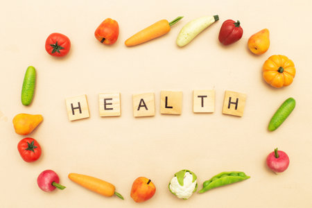 Different healthy food products on a beige background. Health word made by wooden cubes and many fruits and vegetablesの写真素材