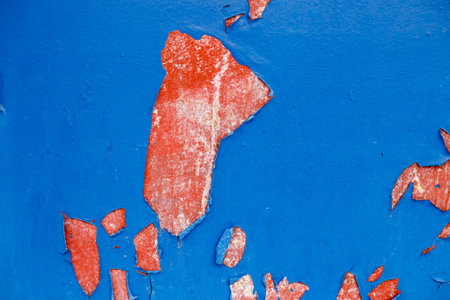 Old blue paint peeling from red concrete wall background. Texture of an old grunge plate with cracked paint with a hole.の写真素材