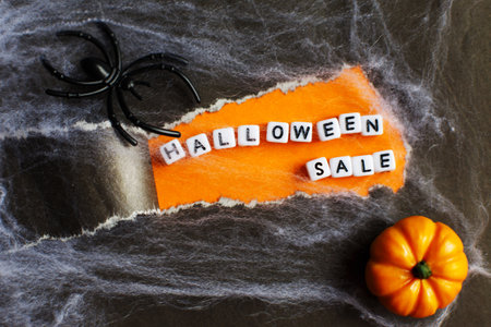 curl of torn black paper on orange background. halloween sale concept.の写真素材