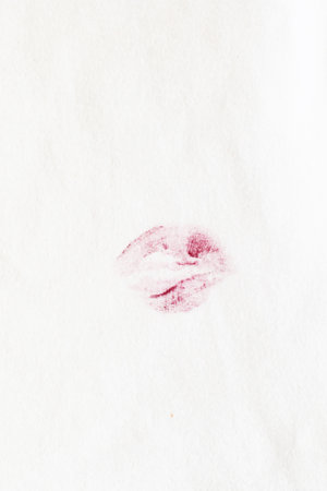 red lipstick kiss stain on white clothes on a beige backgroundの写真素材