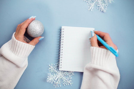 Woman hand with winter nails holding pen on notebook and writing wish list.の写真素材