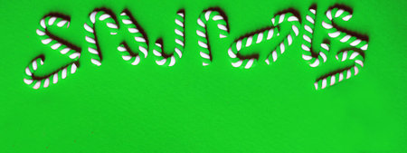 Flat lay Christmas composition with frame of candy canes on a green background. Copy space for text. bannerの写真素材