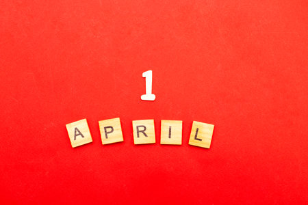 the inscription 1 first April made by wooden cubes on red background. Fools day concept.の写真素材