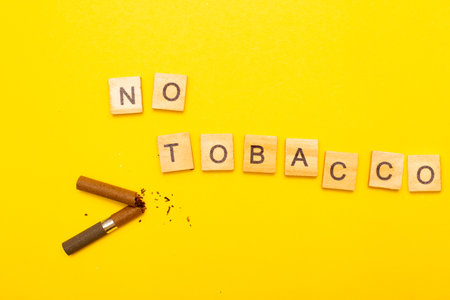 Top view of broken cigarette with the word no tabaco on a yellow background closeup. Addiction, stop smoking and World No Tobacco Day concept.の写真素材