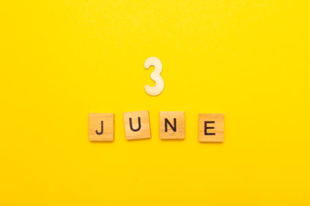 Top view of word 3 June calendar date made by wooden cubes on yellow color background