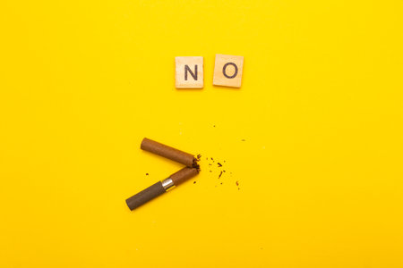 Top view of broken cigarette with the word no on a yellow background closeup. Addiction, stop smoking and World No Tobacco Day concept.の写真素材