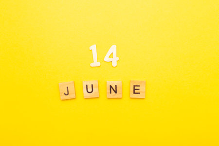 Top view of word 14 June calendar date made by wooden cubes on yellow color background. Calendar and summer concept.の写真素材