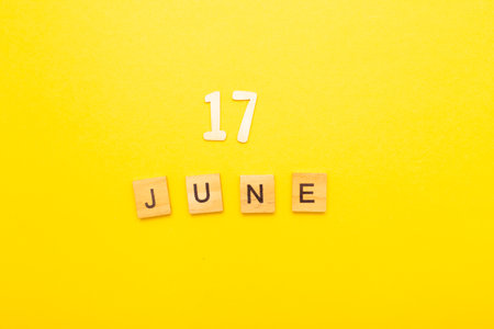Top view of word 17 June calendar date made by wooden cubes on yellow color background. Calendar and summer concept.の写真素材