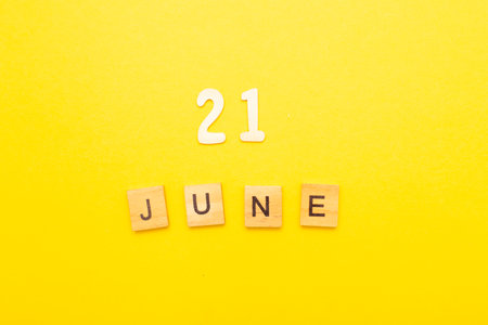 Top view of word 21 June calendar date made by wooden cubes on yellow color background. Calendar and summer concept.の写真素材
