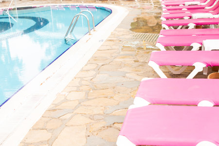 A row of pink deck chairs standing near hotel swimming pool. Summer holidays and vacation concept.の写真素材