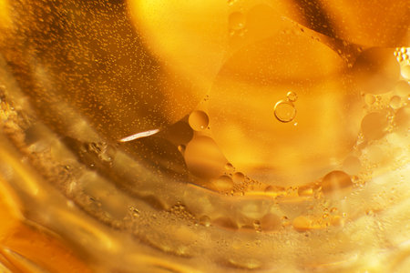 Gold Oil bubbles close up. circles of orange water macro. abstract shiny yellow background.の写真素材