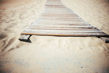 a wooden walkway on the beach lies on the sandの写真素材