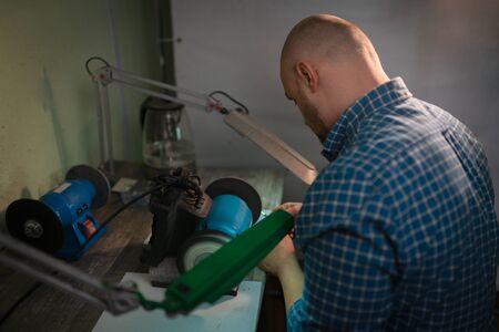 Master sharpens scissors on special equipment for sharpening tool