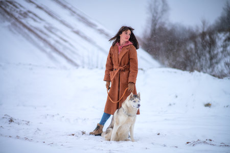 Girl with dog breed husky stands in winter parkの写真素材