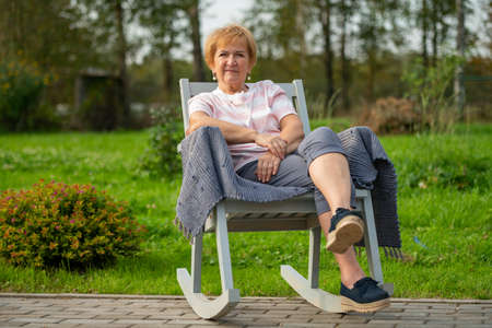 A woman sits in a chair in the fresh airの写真素材