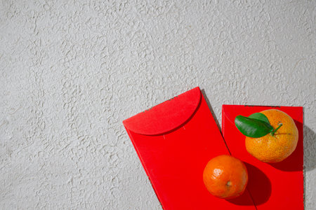 Red angpao and tangerine or mandarin oranges isolated on a white background, symbolizing prosperity, good fortune, and happiness in Chinese celebrationsの写真素材