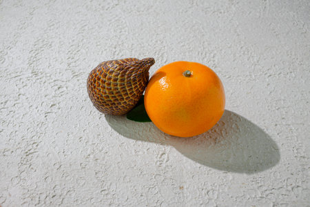 A vibrant orange and snakefruit isolated on a clean white background, representing freshness,...
