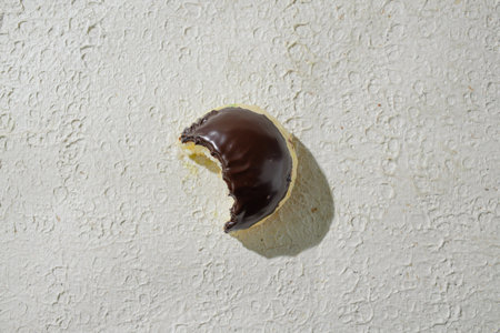 Bitten mini donut with a bite mark visible, set against a textured white background, suggesting taste and textureの写真素材
