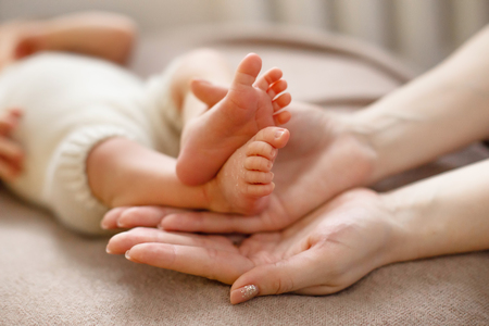 Baby feet cupped into mothers hands. Gentle blurred background of the feet and heels of a newbornの写真素材