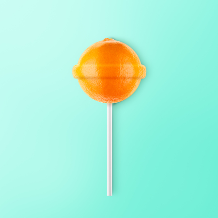 Lollipop orange isolated on blue background. Creative candy ideaの写真素材