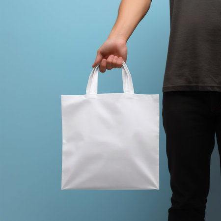 Person Hand Holding a White Blank Tote Bag in Front of a Minimal Background. Generative AI. high quality illustrationの素材