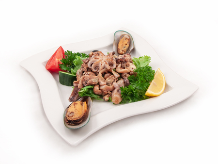 Plate of seafood and fresh vegetables on a white background, close-up, selective focusの写真素材