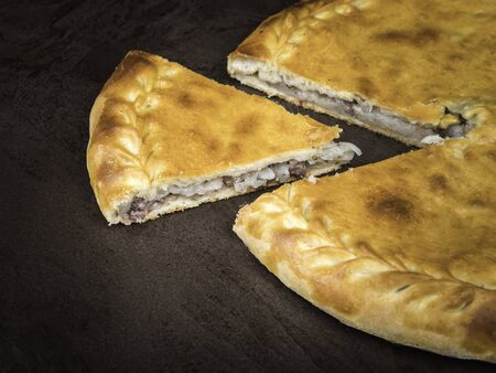 Dagestan meat and potato pie, whole and cut off piece, side view, close-upの写真素材