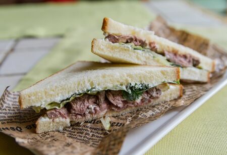 Beef sandwich, lettuce and parsley on a vintage paper close-up, side viewの写真素材